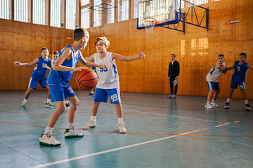Junior basketball team playing basket on training at indoor court.