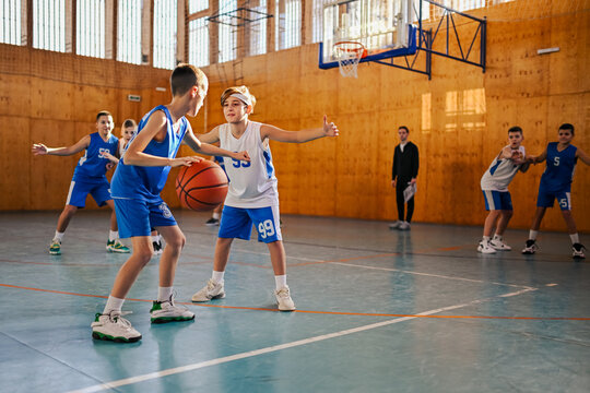 Junior basketball team playing basket on training at indoor court.
