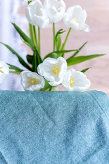 bouquet of white tulips near a table with a blue tablecloth