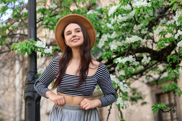 Fototapeta premium Beautiful woman in hat near blossoming tree on spring day