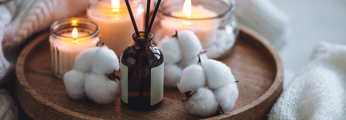 Winter home aromatherapy, cozy atmosphere. Burning aroma candles on wooden tray, knitted blanket,...