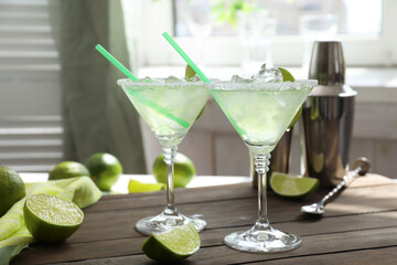 Delicious Margarita cocktail in glasses and lime on wooden table, closeup