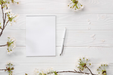 Guest list. Notebook, pen and spring tree branches with beautiful blossoms on white wooden...