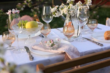 Stylish table setting with beautiful spring flowers in garden