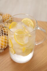 Freshly made lemonade in jug on wooden table indoors