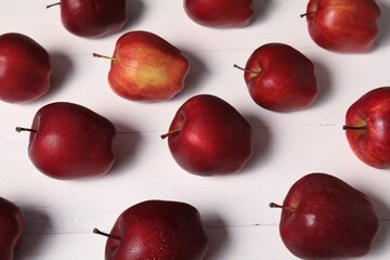 Fresh red apples with water drops on white wooden table