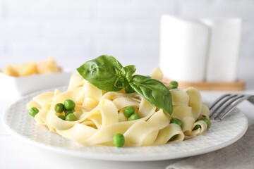 Delicious pasta with green peas served on white table, closeup