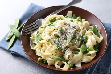 Delicious pasta with green peas and cheese served on grey table