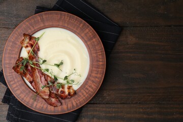 Delicious potato soup with bacon and microgreens in bowl on wooden table, top view. Space for text