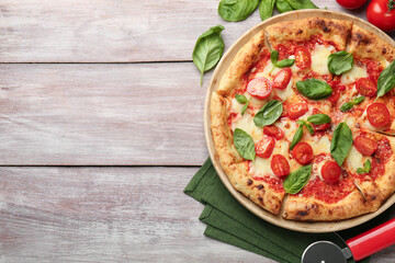 Delicious Margherita pizza and cutter on wooden table, flat lay. Space for text
