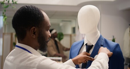 Employee working in clothing store during promotional season, arranging necktie on mannequin...