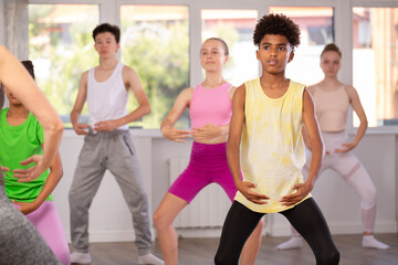Motivated african american teen boy participating in beginner group ballet class, practicing...