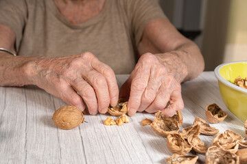 old woman's hands peeling several walnuts