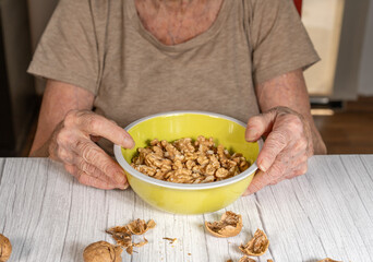 hands of elderly woman holding a bowl with nuts