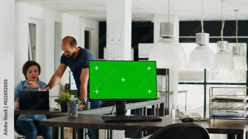 Poster workstation displaying greenscreen layout with copyspace on monitor at empty desk in urban coworking