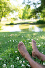 Bare feet of a young African man resting on the green lawn in the park, with copy space