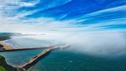 Aerial view of coastal pier with lighthouse and fog in Whitby, North Yorkshire © iSky Media