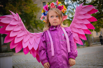 Beautiful young girl wearing pink angel wings. Little cute girl in pink jacket and pink handmade...