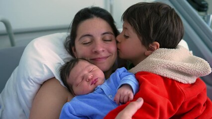 Mother embracing her two children, a newborn and a big brother, highlighting the warmth of family love and connection in a hospital setting. themes of family bonds maternal care, and sibling affection