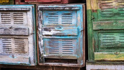 Old beehives featuring faded paint in blue green with peeling and chipping, rustic worn aesthetic....