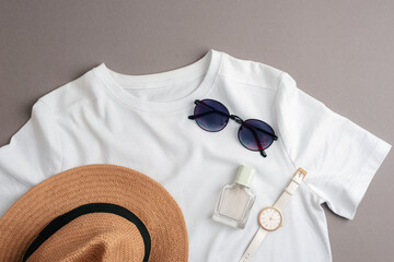 White T-shirt, straw hat, sunglasses, watch and perfume bottle. Overhead view of woman's casual...