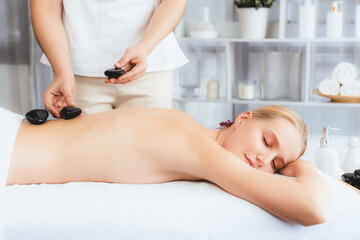 Hot stone massage at spa salon in luxury resort with day light serenity ambient, blissful woman...