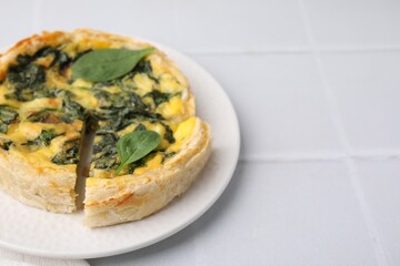 Delicious pie with spinach on white tiled table, closeup. Space for text
