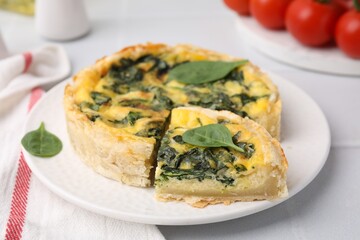 Delicious pie with spinach on white tiled table, closeup