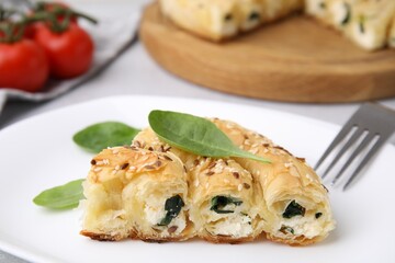 Piece of delicious puff pastry with spinach on table, closeup