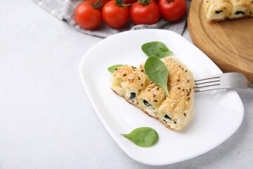 Piece of delicious puff pastry with spinach on light table