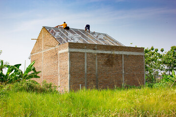 Construction workers on a renovation roof of simple house in the middle of grass