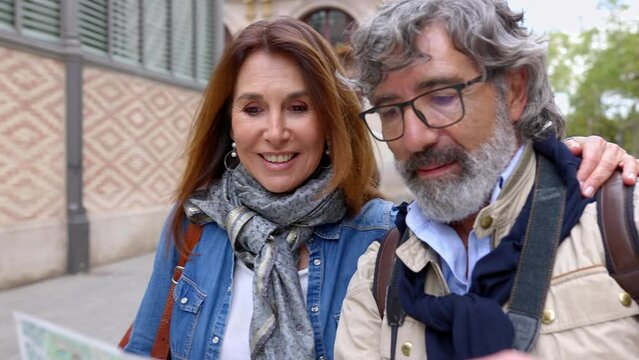 Happy retired senior tourist couple looking for location on city map during travel vacation in Barcelona. Retirement and holiday maker mature people concept.