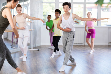 Obraz premium Group of boys and girls teenage dancers performing ballet movements in dance class