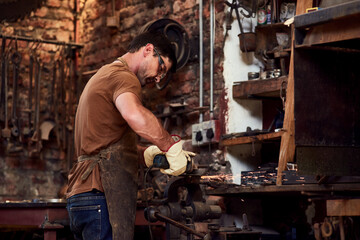 Man, blacksmith and welding sparks or metal production in warehouse as manufacturing, factory or...