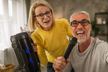 Mature man hold microphone and sign while mature wife hold loudspeaker