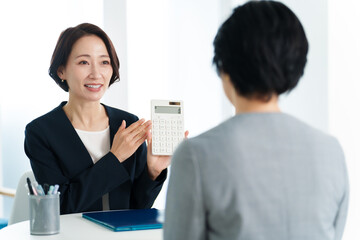 電卓を使って打ち合わせをするビジネスウーマン　資産運用　投資　NISA　コンセプトイメージ