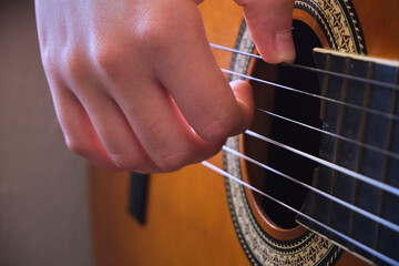 Human hand playing brown guitar
