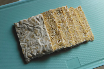 Raw Tempeh or Tempeh. Tempeh slices on a cutting board. Tempeh is made from fermented soybeans.
