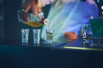 Barman, bottle and pour in shot glasses at night club for service, order and counter server with...
