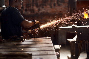 Blacksmith, metal work or man in workshop and sparks, manual labor for safety on hot steel with...