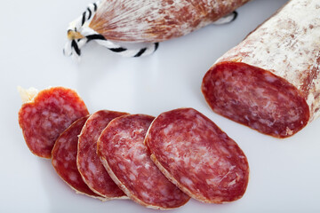 Sliced dry cured sausage Llonganissa from Catalonia on white background. Traditional Spanish meat...