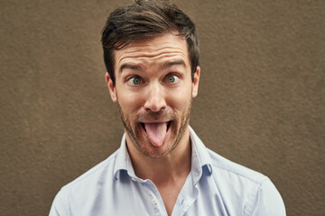 Man, tongue and funny face on isolated background in silly, goofy or comedy on mockup or wall backdrop. Comic, emoji or happy comedian guy in quirky pose, joke style trend or facial expression