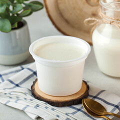 Creamy natural yogurt in a simple white container, perfect for a healthy and nutritious snack.