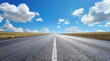 endless open road empty asphalt highway stretching to blue sky with fluffy white clouds
