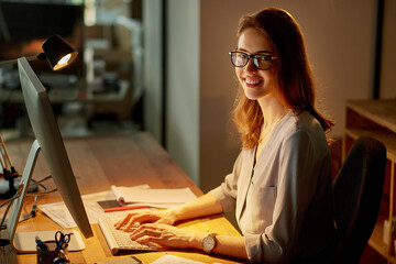 Night, woman and happy on computer in office for career or job growth with opportunity. Female...