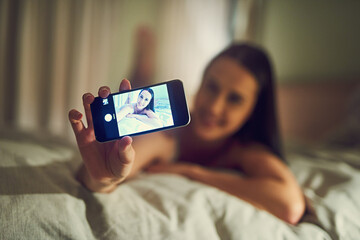 Selfie, phone screen and woman on bed at night for social media, live streaming and portrait in...