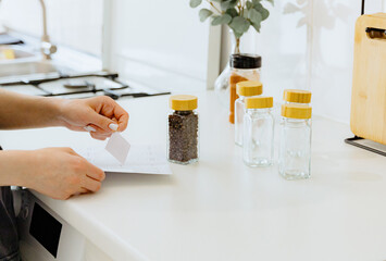 A girl peels off a sticker for a jar of black pea spice.