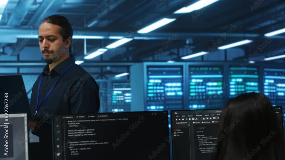Poster manager overseeing server room, running code on laptop, troubleshooting and upgrading technologicall