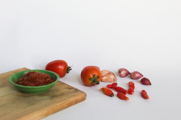 Portrait of tomato chili sauce in a green bowl isolated on a white background, seasoned with tomatoes, chilies, shallots, garlic.