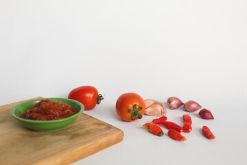 Portrait of tomato chili sauce in a green bowl isolated on a white background, seasoned with tomatoes, chilies, shallots, garlic.